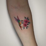 Color realism tattoo of an Andean hummingbird drinking nectar from a pink kantuta flower, created at NOIR Tattoo Studio in Cusco, Peru.
