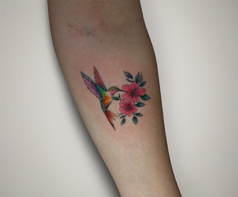 Color realism tattoo of an Andean hummingbird drinking nectar from a pink kantuta flower, created at NOIR Tattoo Studio in Cusco, Peru.