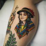 Traditional tattoo of a Cusqueña woman wearing a colorful Andean poncho and hat with kantuta flowers, created at NOIR Tattoo Studio in Cusco, Peru.