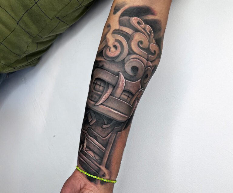 Black and grey realism tattoo inspired by Pre-Columbian Andean culture, featuring ancient mask and ornamental motifs, created at NOIR Tattoo Studio in Cusco, Peru.