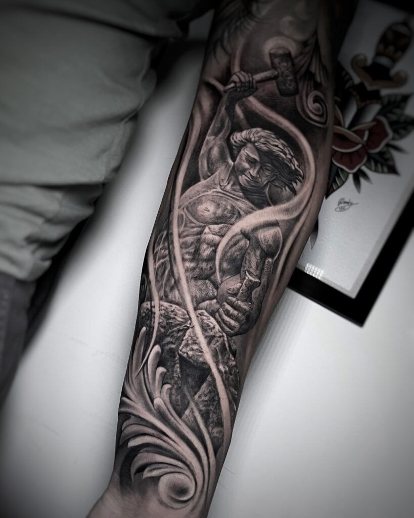Black and grey realism tattoo of a man sculpting his own body from stone, symbolizing self-creation, discipline, and transformation. Created at NOIR Tattoo Studio in Cusco, Peru.