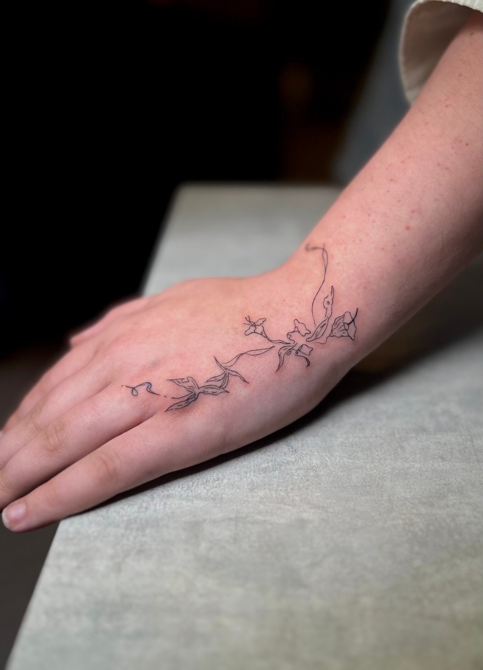 Fine line blackwork tattoo of a bird in flight surrounded by geometric elements and leaves, symbolizing freedom and growth, created at NOIR Tattoo Studio in Cusco, Peru.