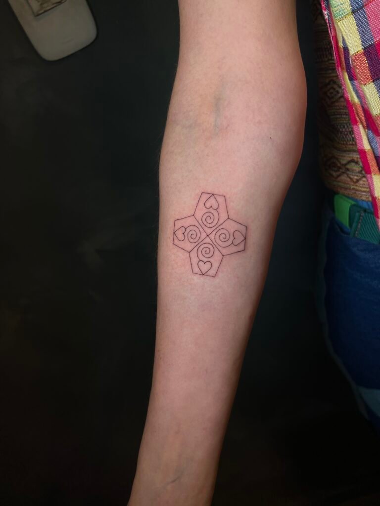 Fine line tattoo of a chakana, the Andean cross symbol representing balance and connection between the spiritual and earthly worlds, created at NOIR Tattoo Studio in Cusco, Peru.