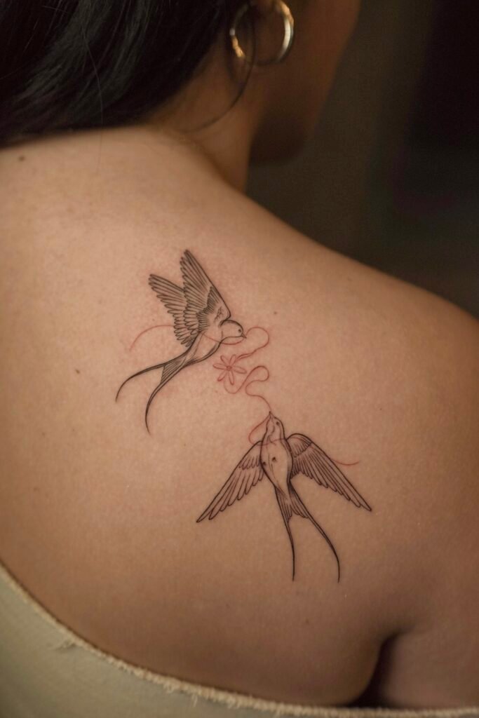 Minimalist fineline tattoo of two swallows connected by a red thread, symbolizing love, destiny, and eternal connection. Created at NOIR Tattoo Cusco, Peru.