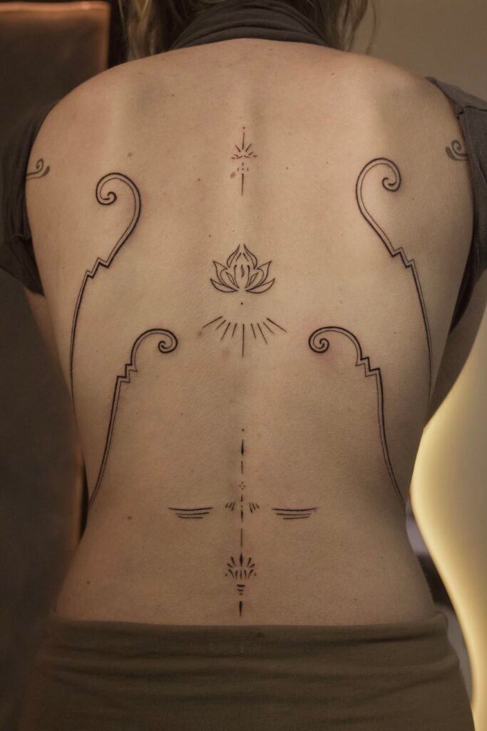 Delicate ornamental fineline tattoo along the spine featuring sacred lotus and geometric elements, symbolizing balance, purity, and spiritual awakening. Created at NOIR Tattoo Cusco, Peru.