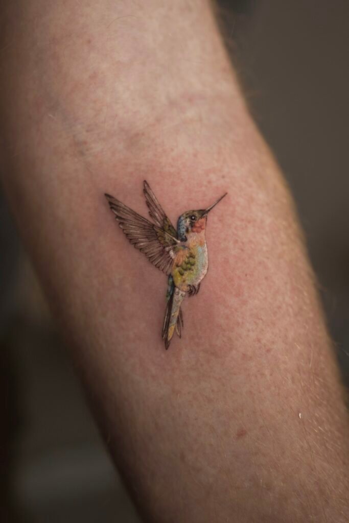 Realistic micro tattoo of an Andean hummingbird in flight, symbolizing freedom, energy, and connection to nature. Created at NOIR Tattoo Cusco, Peru.