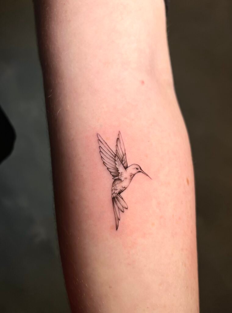Fine line tattoo of a hummingbird in flight, symbolizing freedom, energy, and the spirit of the Andes, created at NOIR Tattoo Studio in Cusco, Peru.