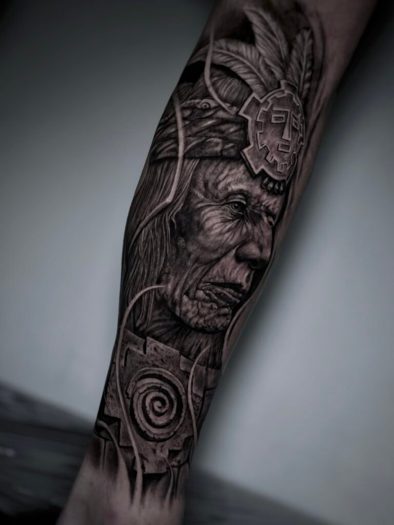 Black and grey realism tattoo of an Andean elder with ancestral symbols, representing wisdom, connection to the earth, and cultural identity. Created at NOIR Tattoo Studio in Cusco, Peru.