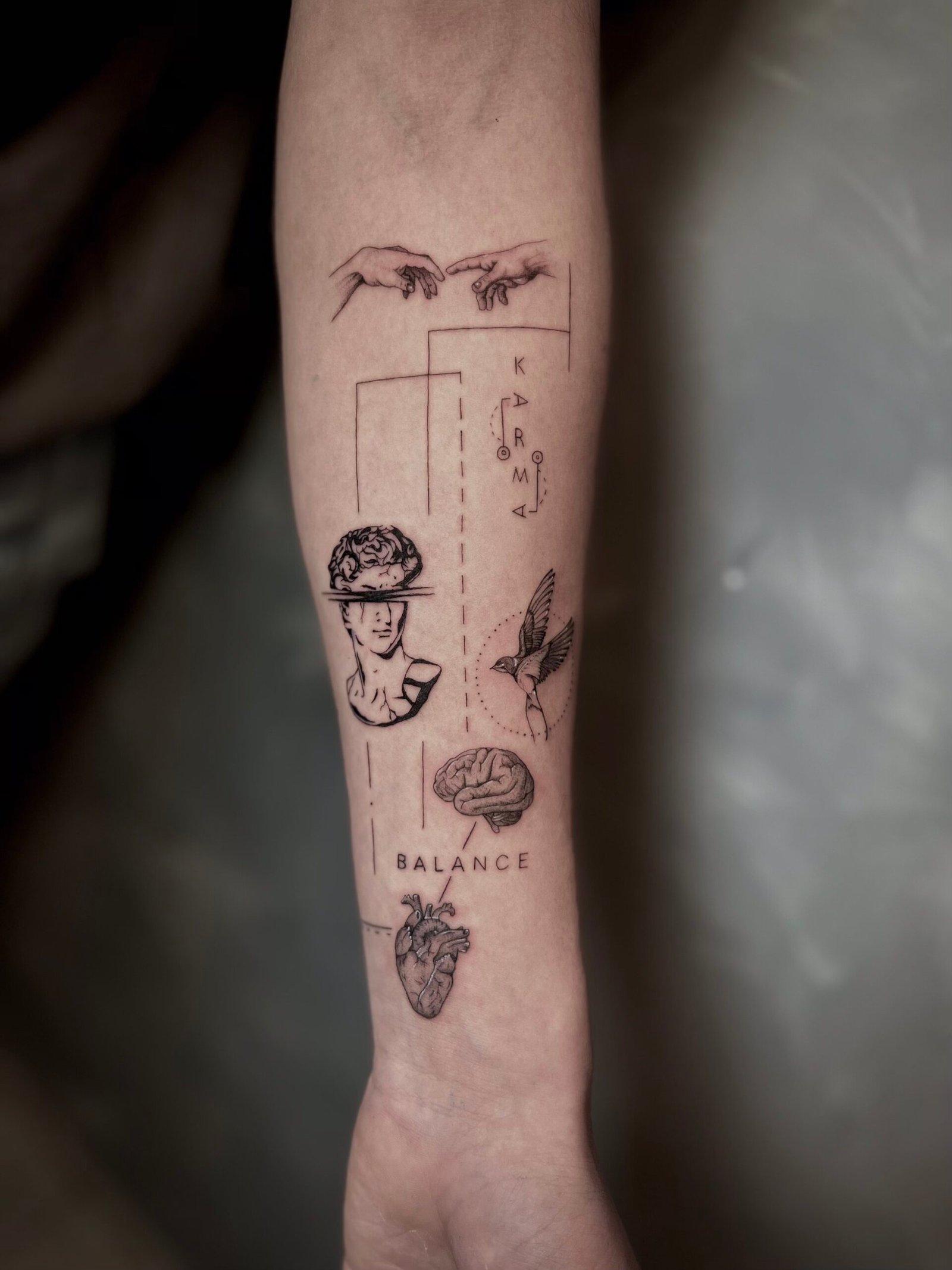Fine line tattoo featuring symbolic elements of balance: the brain, heart, a classical statue, geometric lines, a bird, and Michelangelo’s hands of creation, created at NOIR Tattoo Studio in Cusco, Peru.