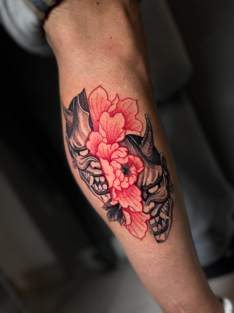 Japanese tattoo featuring dual Hannya masks with a vibrant red peony flower, symbolizing the balance between passion, beauty, and inner duality — created at NOIR Tattoo Cusco, Peru.