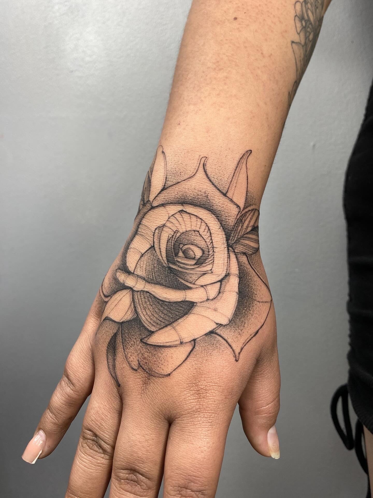 Sketch-style tattoo of a rose on the hand, featuring expressive linework and artistic shading. Created at NOIR Tattoo Cusco, Peru.