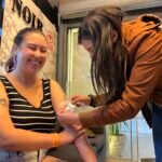 Tattoo artist from NOIR Tattoo Cusco sharing a joyful moment with an American client after finishing a tattoo, highlighting connection and artistic experience in Cusco, Peru.