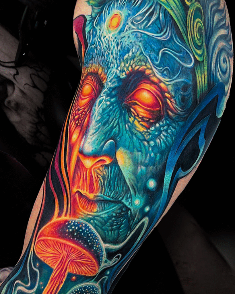Vibrant color realism tattoo of a psychedelic face with glowing eyes, third eye, and mushrooms, symbolizing spiritual awakening and consciousness expansion. Created at NOIR Tattoo Studio in Cusco, Peru.