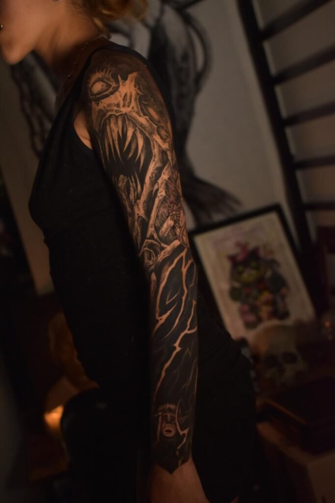 Dark blackwork sleeve tattoo with horror-inspired design created at NOIR Tattoo Cusco in Peru.
