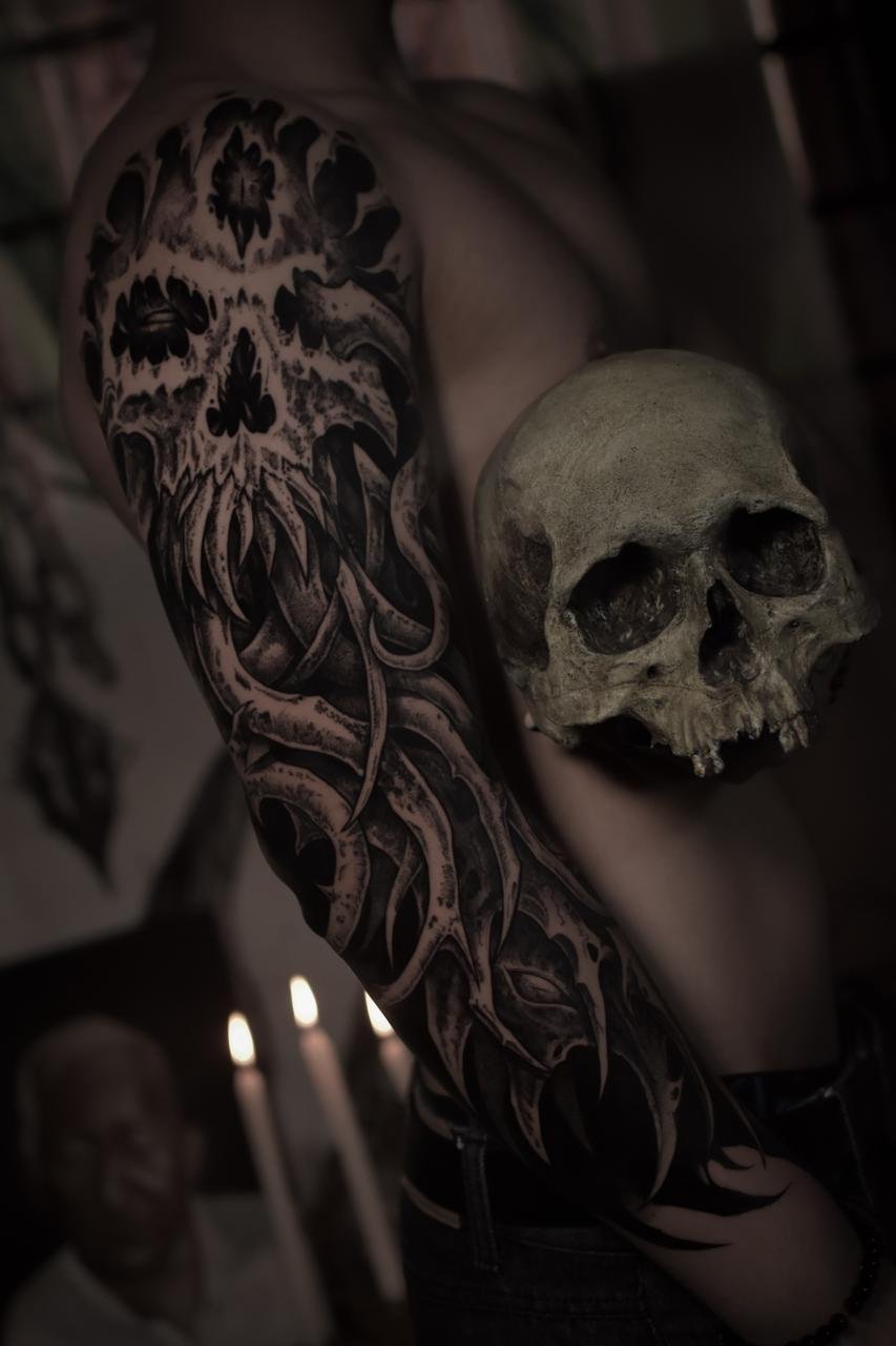 Black and grey Buddha sleeve tattoo with mandala, lotus, and sacred geometry dotwork on a woman’s arm, symbolizing peace, mindfulness, and spiritual protection — NOIR Tattoo Cusco.