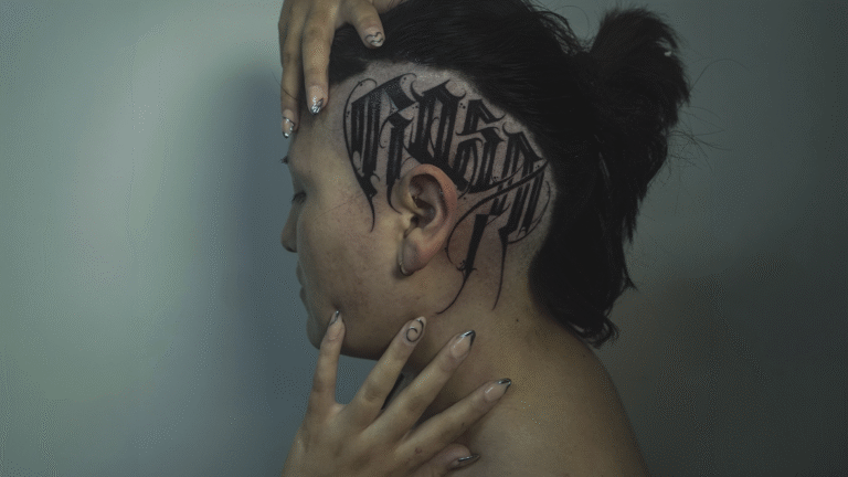Custom blackwork calligraphy scalp tattoo with gothic lettering on the side of the head, tattooed at Noir Tattoo Cusco, Peru.