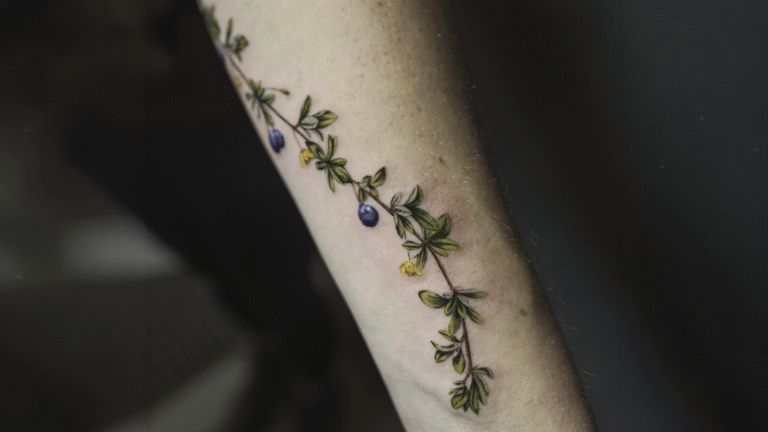 Delicate fine line blueberry branch tattoo with botanical illustration and soft natural colors, tattooed at Noir Tattoo Cusco, Peru.