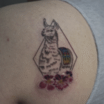 Fine line llama tattoo with colorful Andean textile details and flowers, inspired by Peruvian culture and created in Cusco, Peru.
