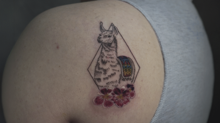 Fine line llama tattoo with colorful Andean textile details and flowers, inspired by Peruvian culture and created in Cusco, Peru.