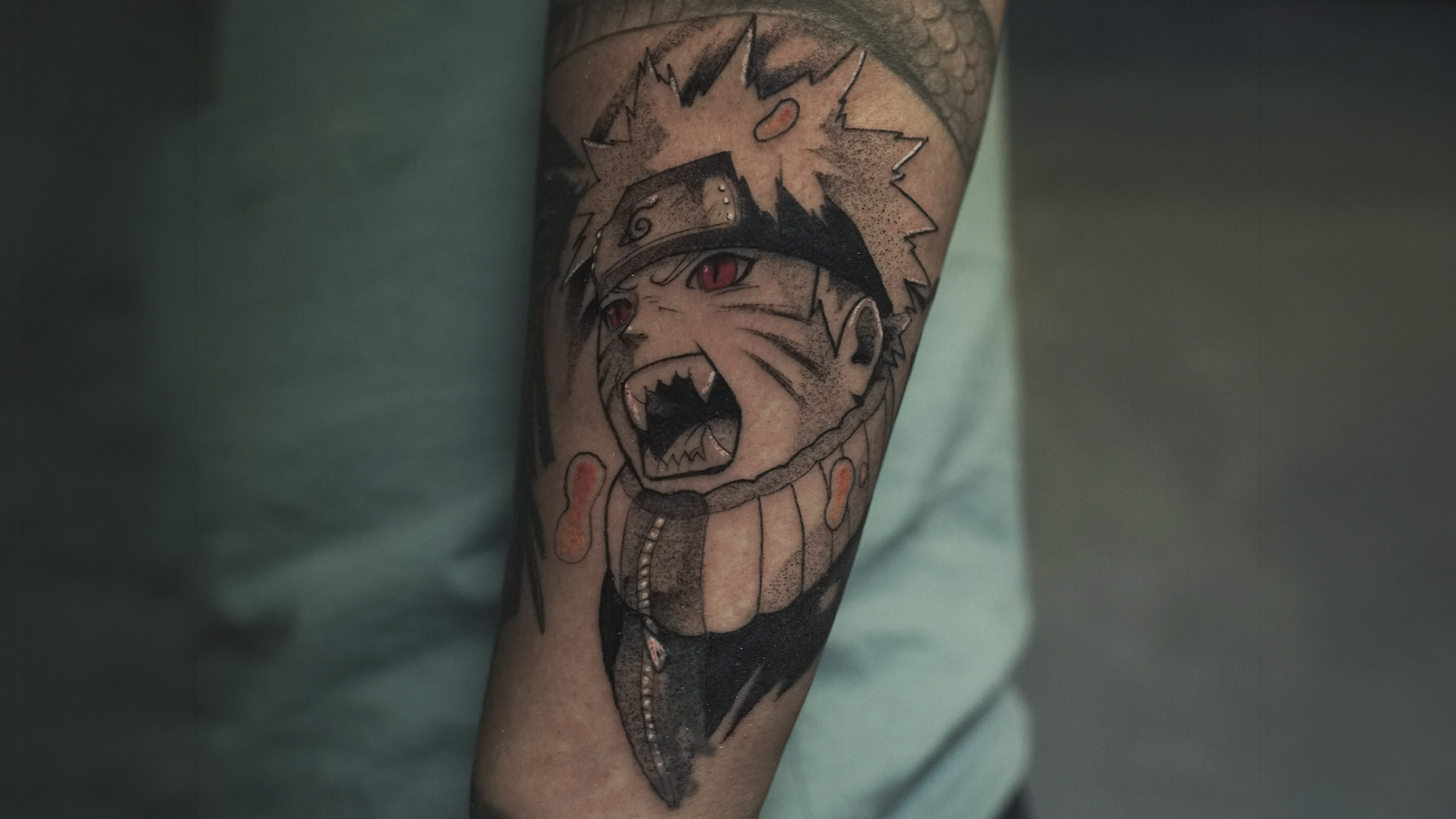 Black and grey Naruto Uzumaki tattoo with red eyes inspired by the Nine-Tails transformation, created at Noir Tattoo Cusco, Peru.