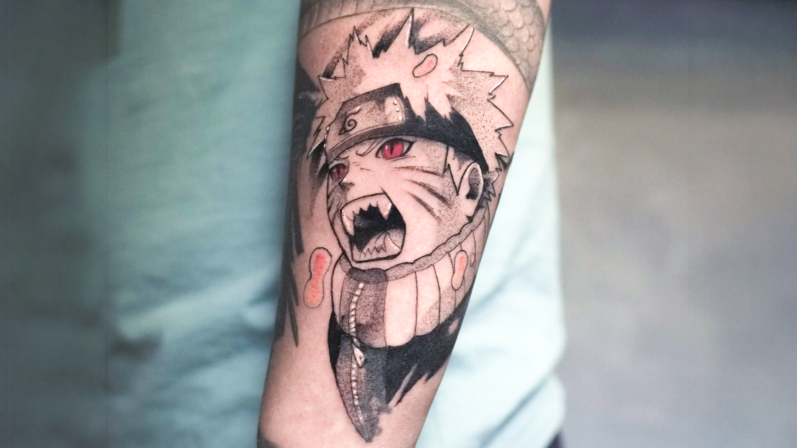 Naruto anime tattoo in black and grey with red eyes on the forearm at Noir Tattoo Cusco