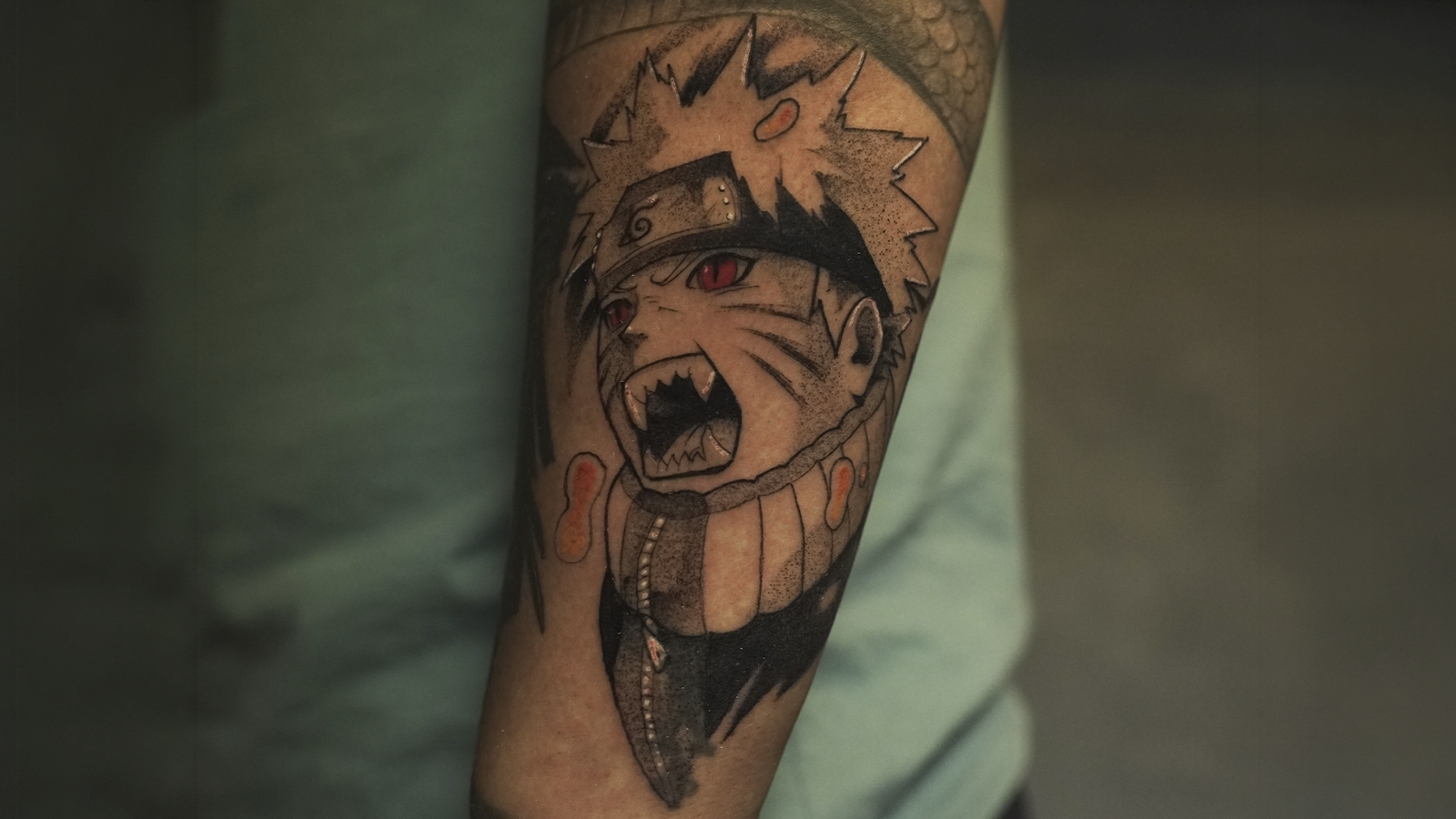 Black and grey Naruto Uzumaki tattoo with red eyes inspired by the Nine-Tails transformation, created at Noir Tattoo Cusco, Peru.