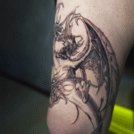Dark fantasy dragon tattoo in black and grey featuring gothic details, demonic wings, and intricate linework, tattooed at Noir Tattoo Cusco, Peru.