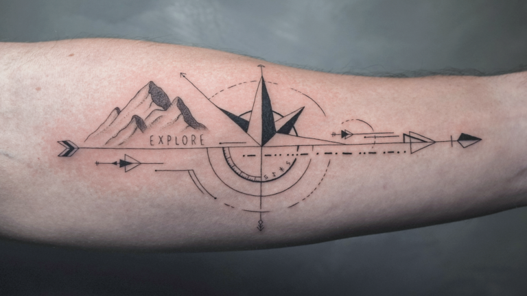 Geometric compass and mountain tattoo on the forearm with the word "Explore," symbolizing adventure, travel, and direction.