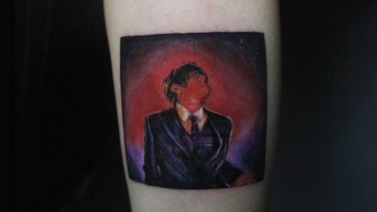 Color realism tattoo inspired by a music album cover featuring a dramatic portrait with cinematic lighting, tattooed at Noir Tattoo Cusco, Peru.