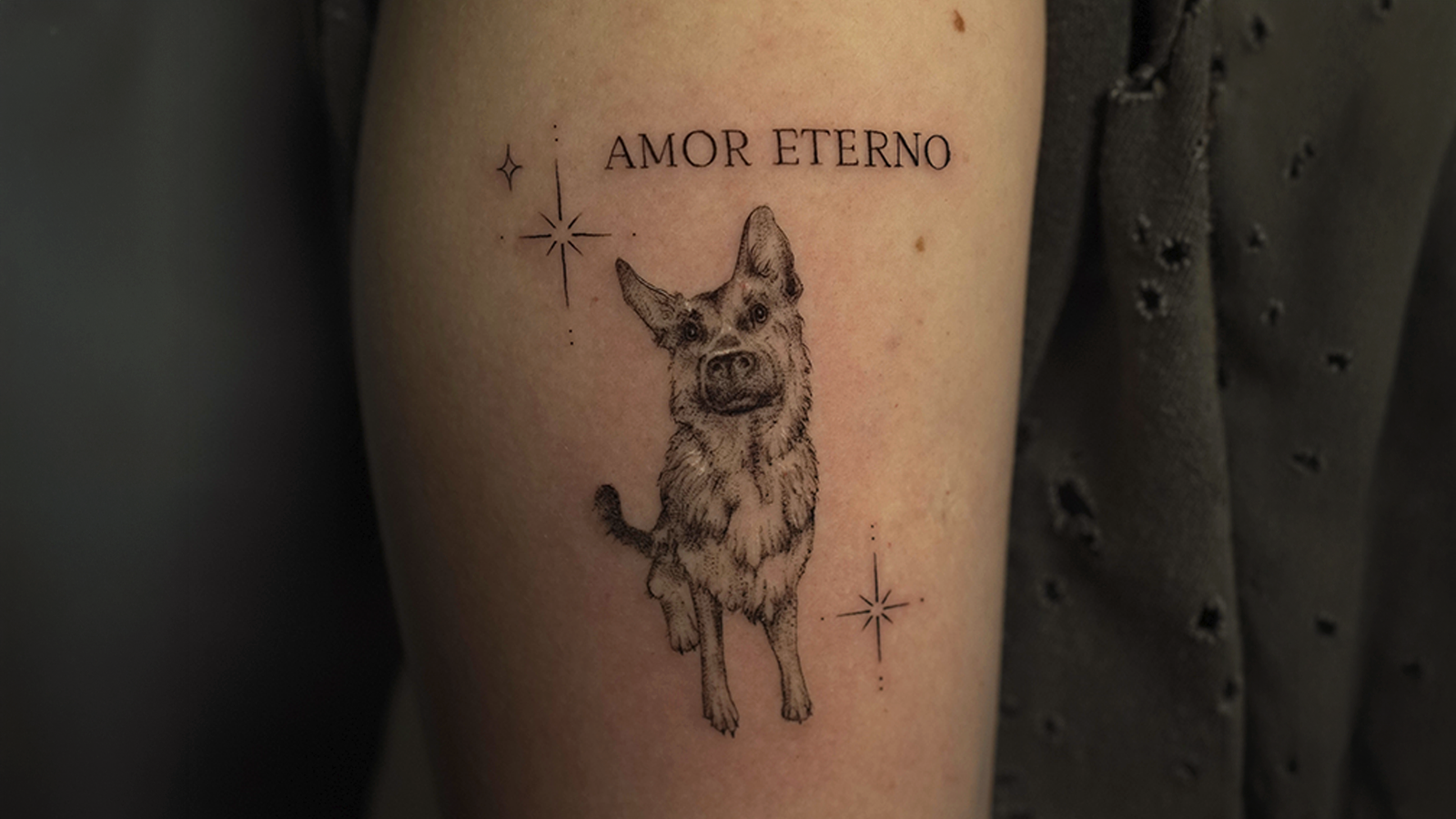 Fine-line pet memorial tattoo with a dog portrait, stars, and the words Amor Eterno, created in Cusco, Peru